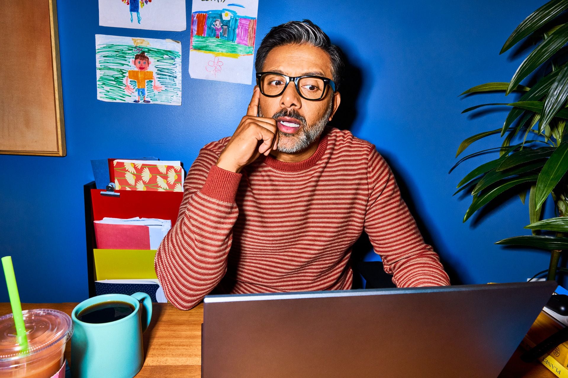 A HR manager in his home office looks thoughtfully at his laptop screen while learning about the complexities of how to hire globally.