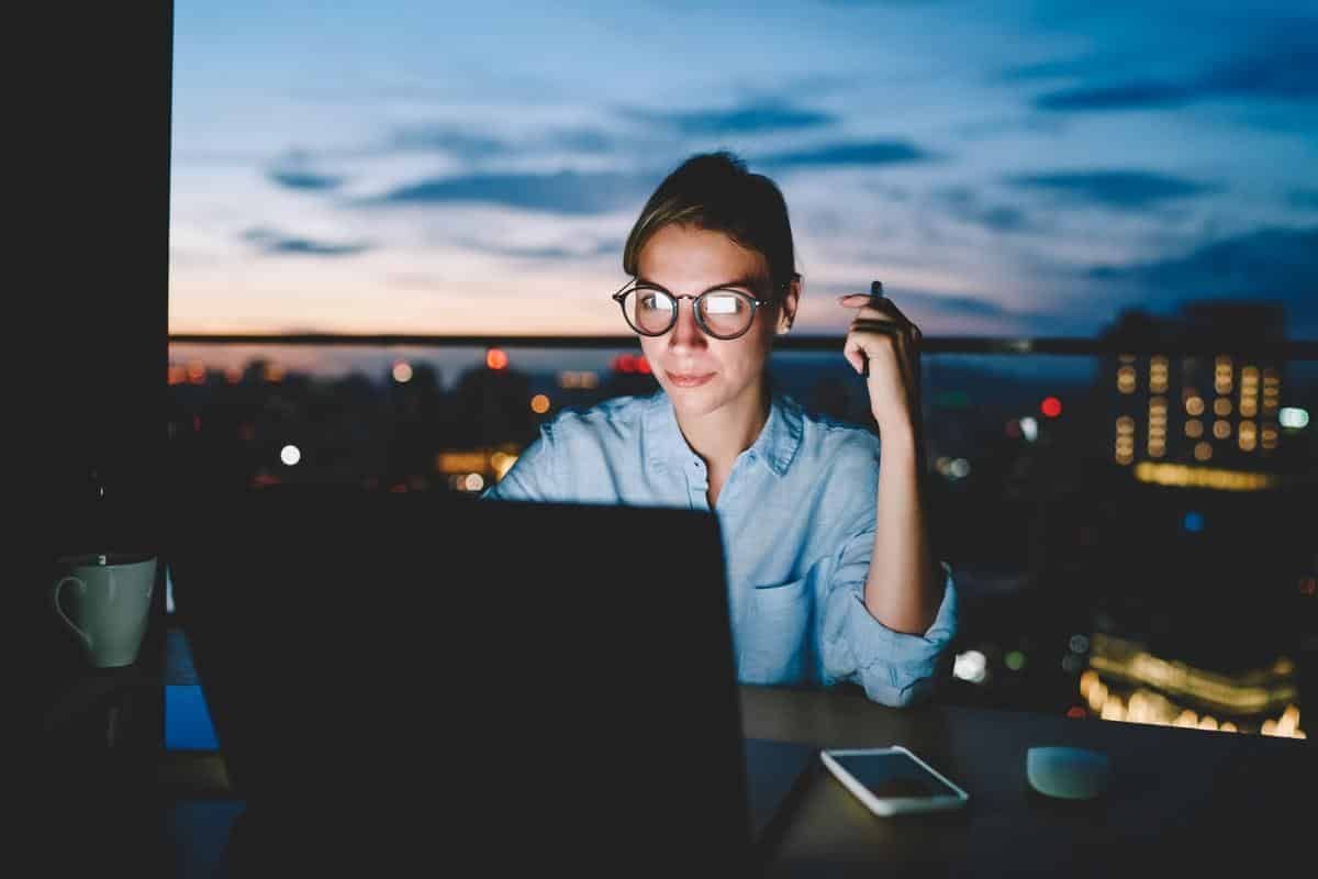 Young female owner of online startup working overtime at home in