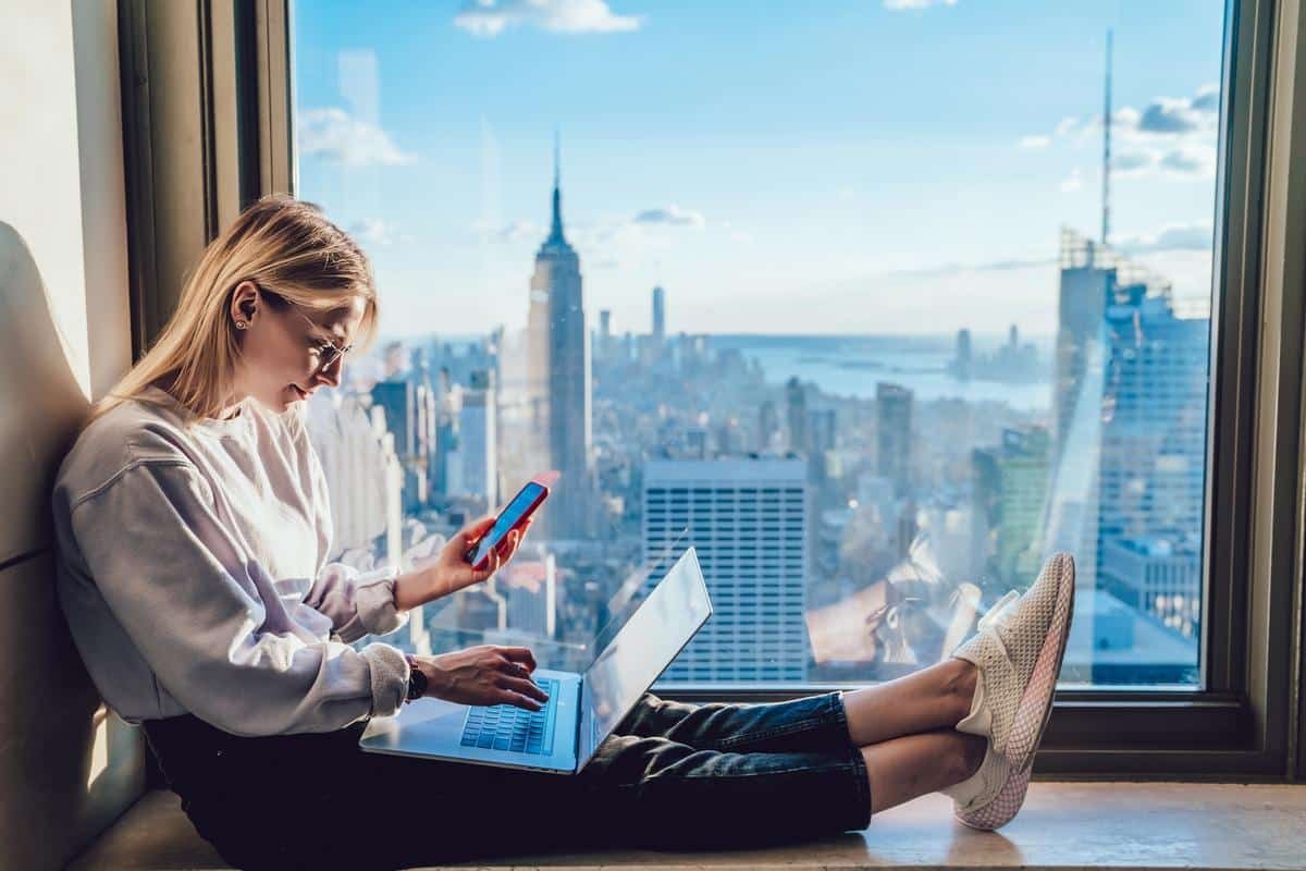 Millennial hipster girl typing text on laptop keyboard while hol