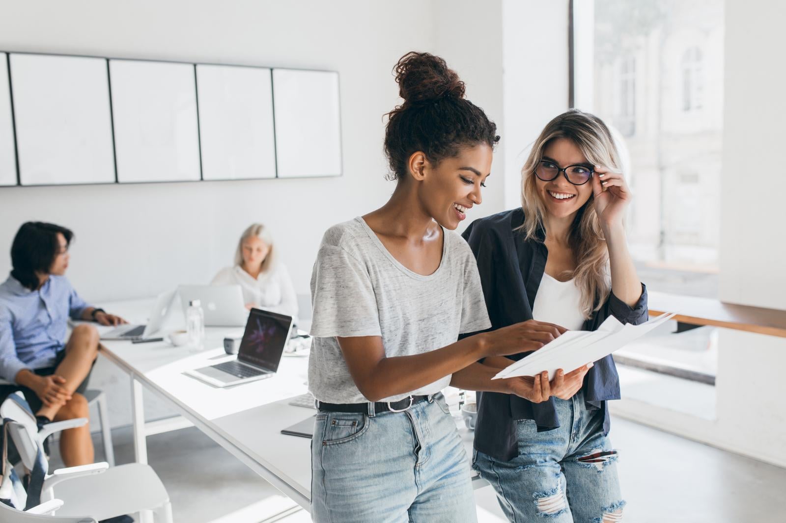 Two young women professionals looking at notes in an office