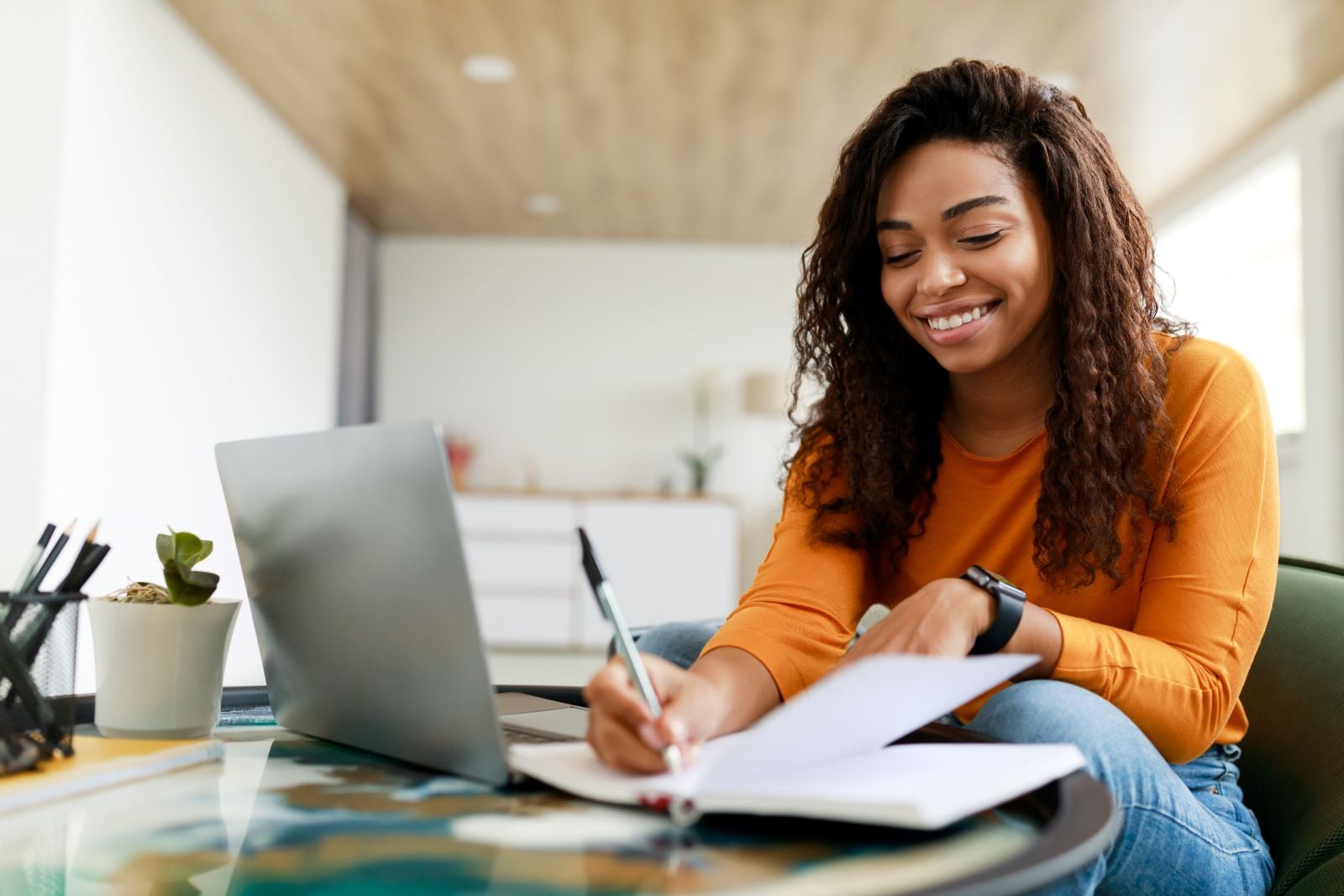 Woman professional with her laptop, writing notes at her desk