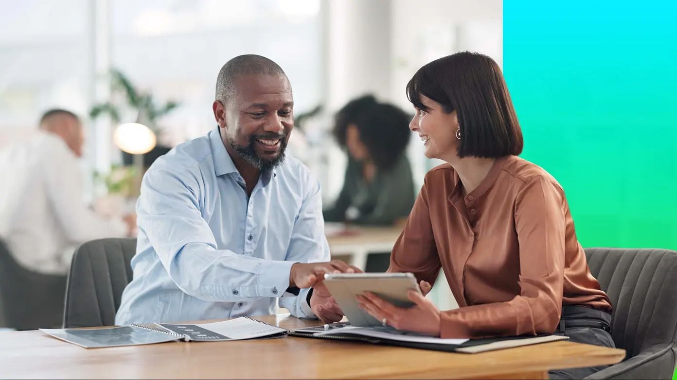 man and woman looking at business reports and information on an ipad
